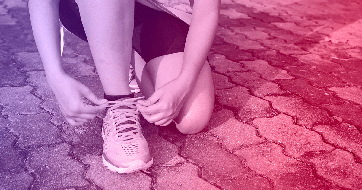 A woman lacing up a pair of trainers.